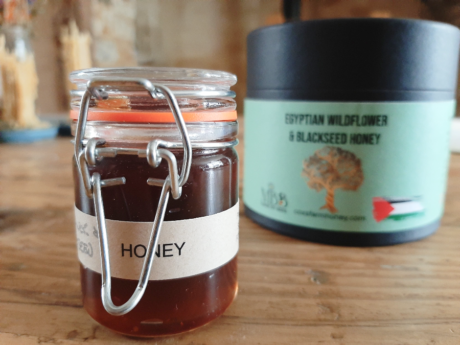 jar in foreground of Egyptian wildflower and black seed honey