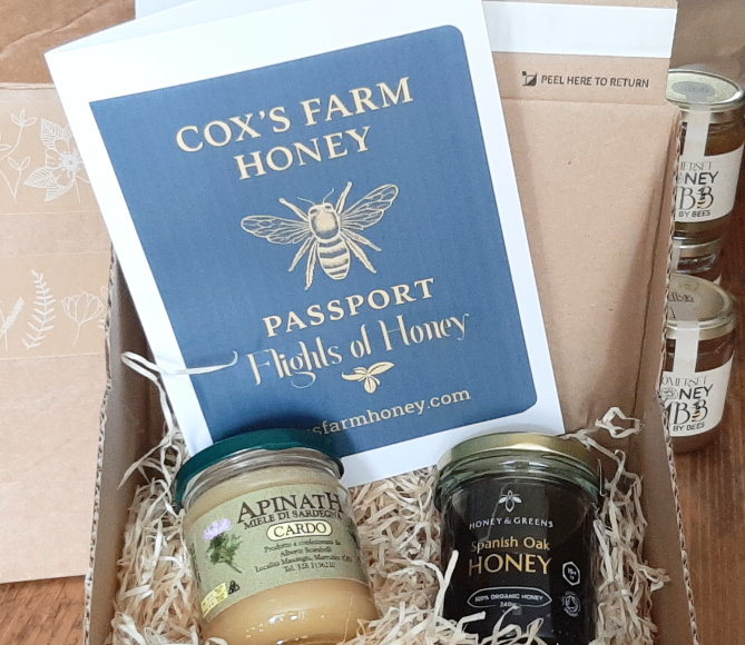 Box of honey jars with a 'Cox's Farm Honey' passport and packaging.