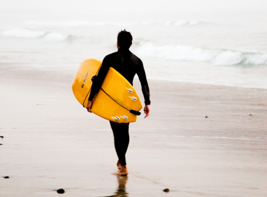 surf board wax - surfer with board walking to ocean