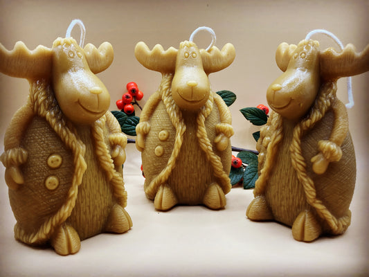 trio of cute moose in coat candles with christmas scene in background